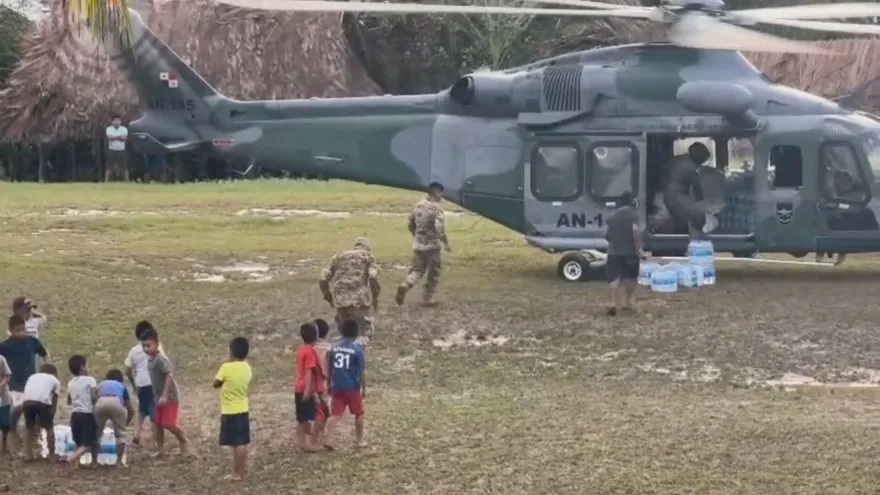Floodwaters rushing through a rural indigenous community in Panama, with damaged roads and homes nearby