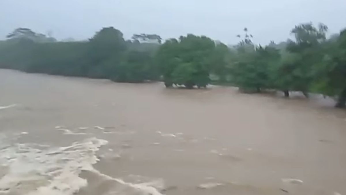 A swollen river in a rural mountain area of Panama after heavy rainfall, with muddy rushing water and dense green surroundings.