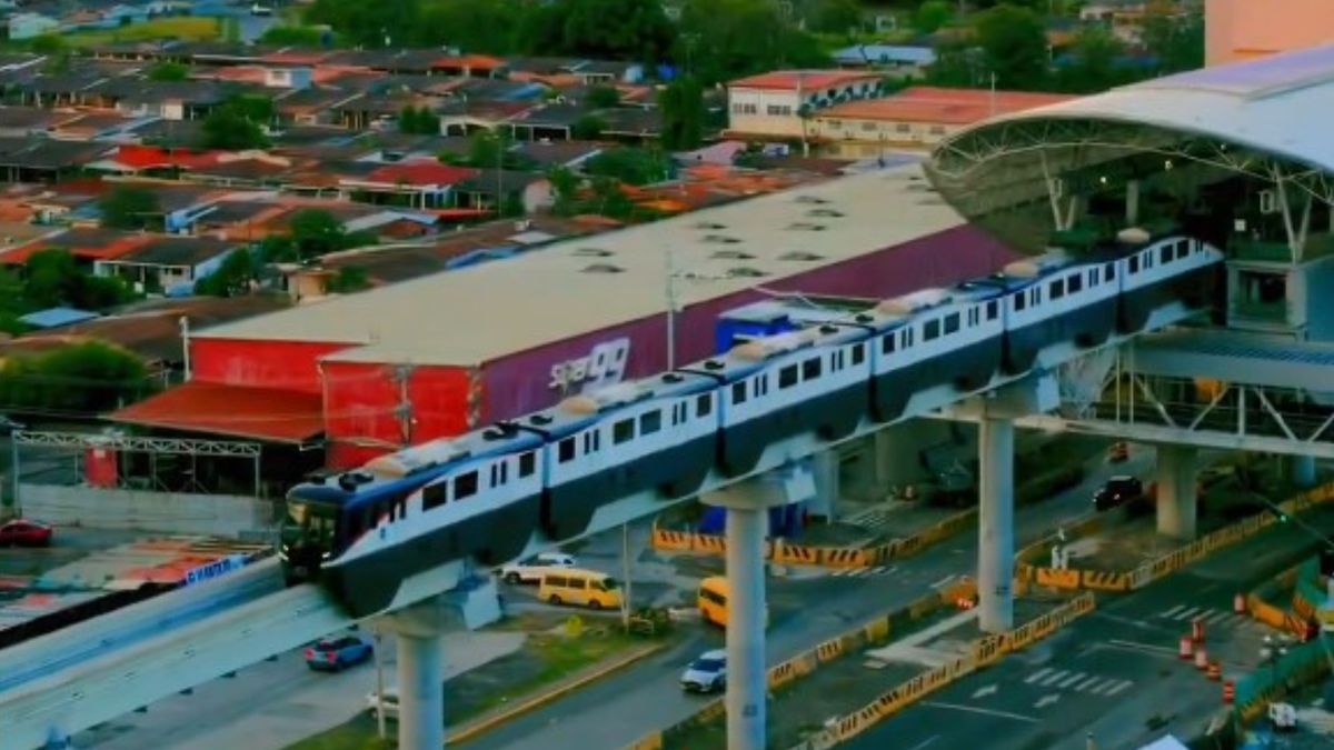 Commuters in traffic on a busy highway in Panamá Oeste with Metro de Panamá Line 3 monorail infrastructure in the background