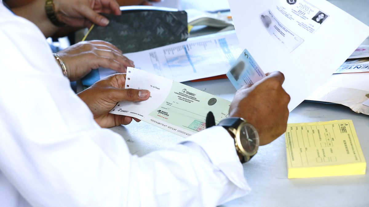 A Panamanian student in school uniform standing outside a school building with a backpack