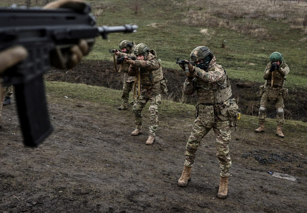 A Ukrainian soldier in fatigues standing near a damaged military position during the ongoing war