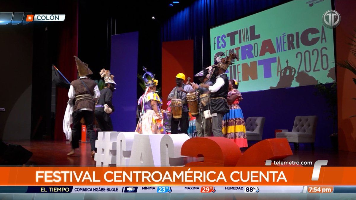 People attending a literary and cultural festival in Colón, Panama, with stage seating and event banners