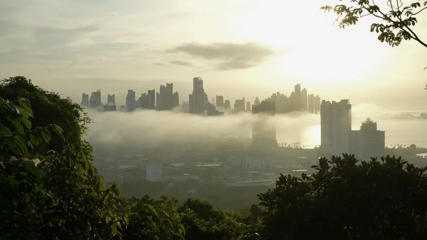 A cloudy tropical sky over Panama with bright sun breaking through and a person carrying an umbrella in hot weather