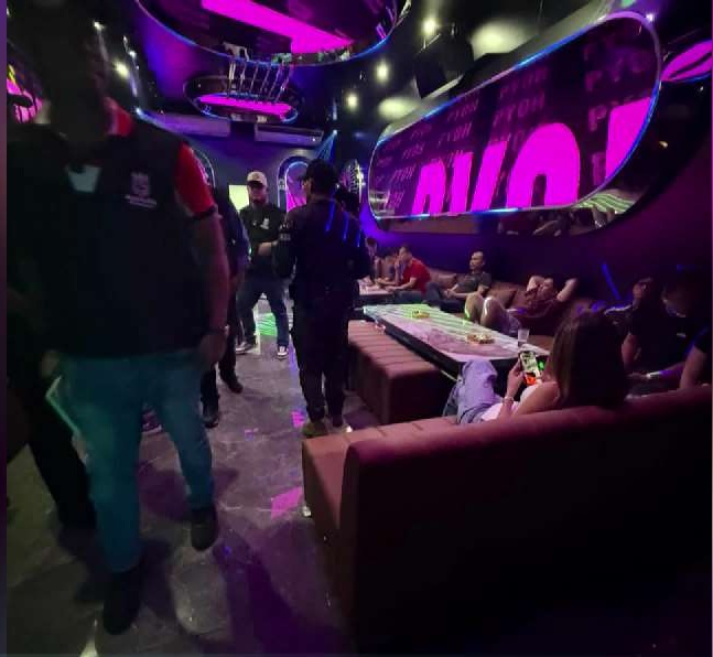 Municipal officers inspecting and dismantling an illegal bar in Condado del Rey with seized beer cases and sound equipment