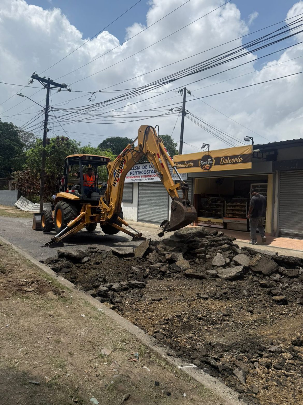 Workers and municipal officials overseeing asphalt repairs on a neighborhood street in Panama Norte