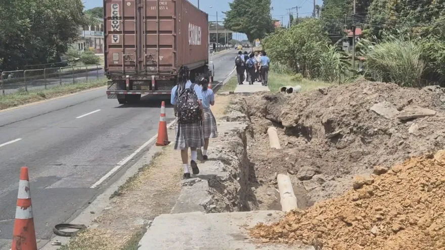 Students walking near the Inter-American Highway beside a school area in Chame, Panama, with traffic moving nearby