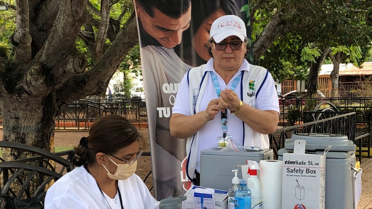A healthcare worker preparing a child vaccination dose in a Panama clinic while public health officials monitor measles prevention